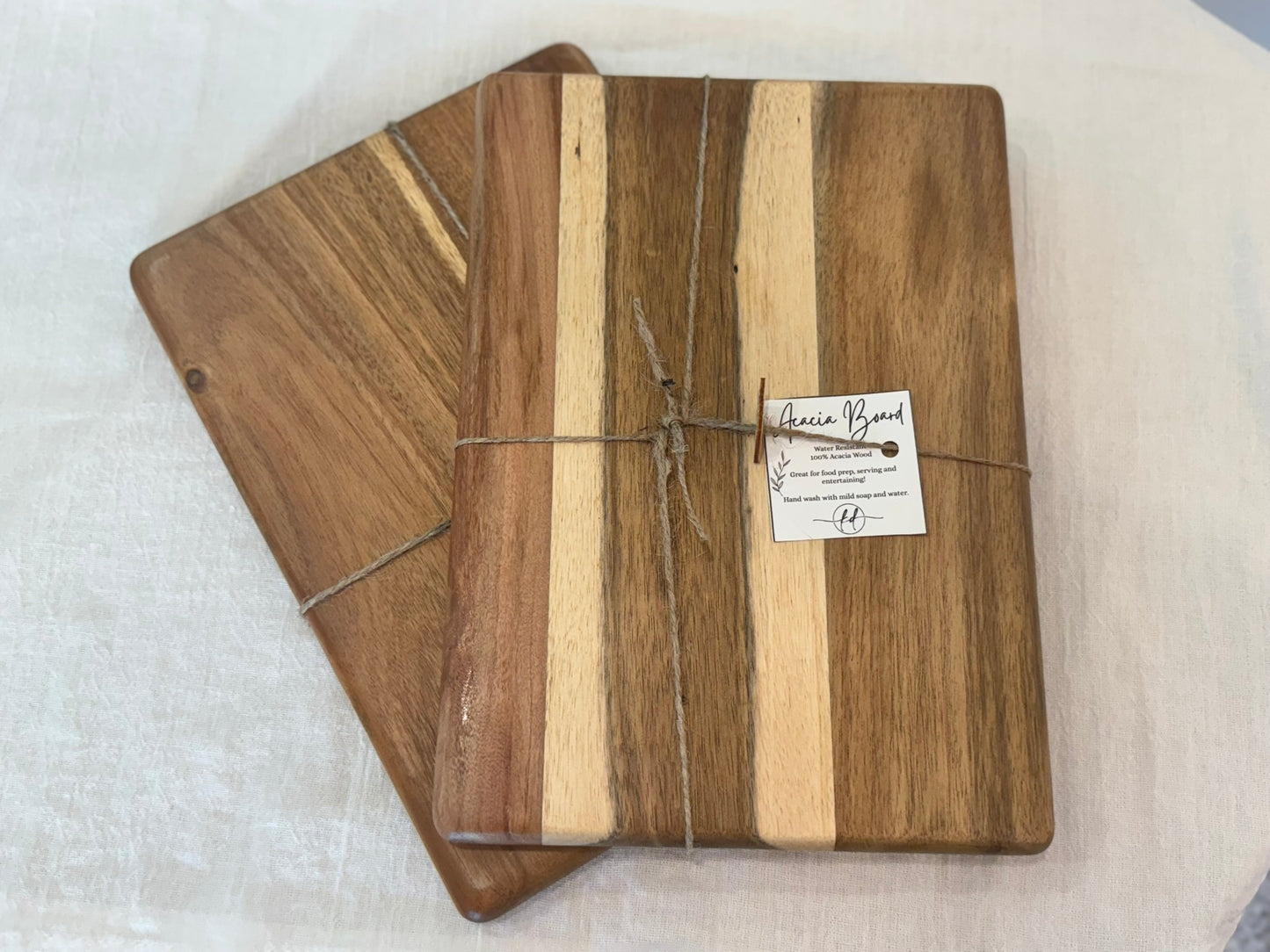 Two wooden cutting boards with a visible brand label on a white surface
